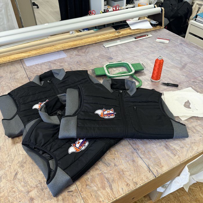 Vêtements marqués posés sur l'établi de l'atelier Markage.TOP, prêts pour le contrôle qualité